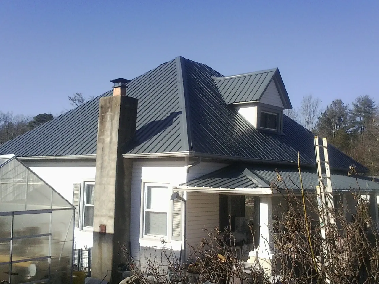 Dark blue standing seam metal roof on a white farmhouse with dormer — Slate & Tile Roof Repair by Roofing Brothers in Parish