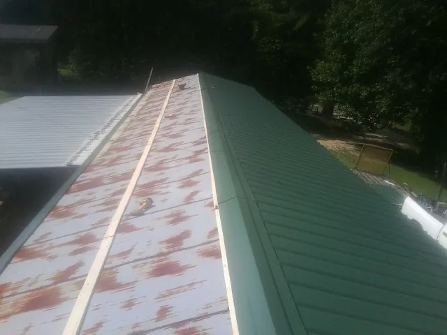 Old rusted panels beside newly installed green metal roofing — Wind Damage Roof Repair by Roofing Brothers in Parish