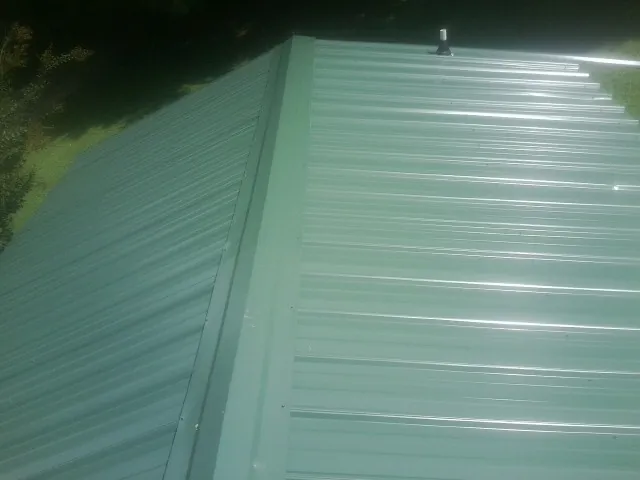 New green metal panels meeting at the ridge of a roof — Flat Roof Repair work by our crew in Parish