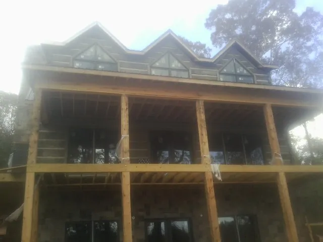 Dormers and porch framing on a large log home under construction — Roof Coating work by our crew in Parish