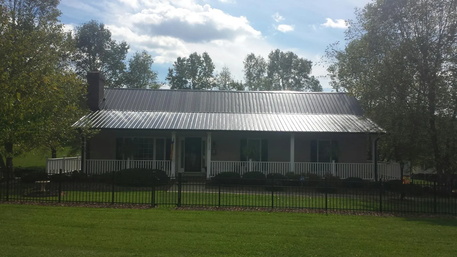 Gray metal roof on a brick ranch with a full width front porch — Gutter Guard Installation work by our crew in Parish