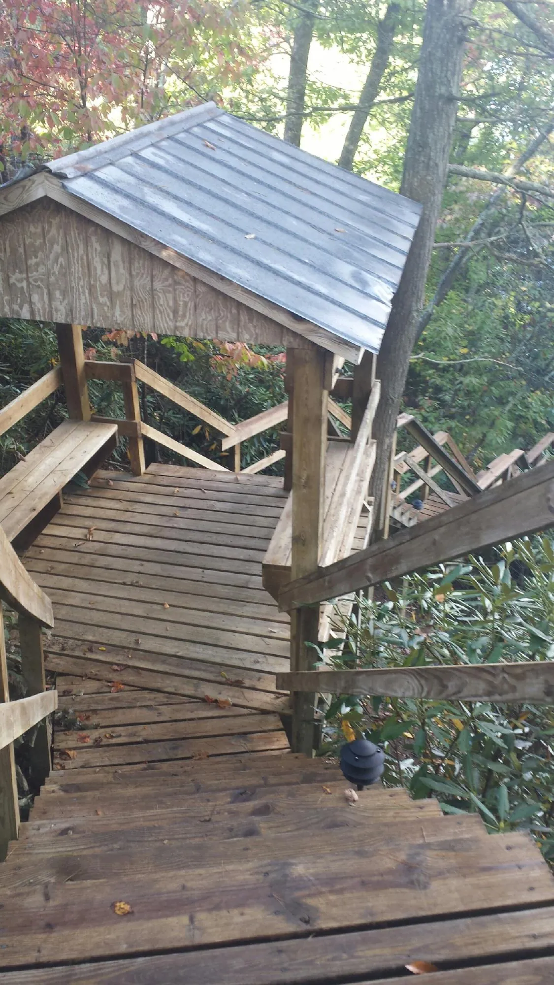 Metal roofed shelter over wooden steps on a wooded walkway — Skylight Repair & Installation work by our crew in Parish